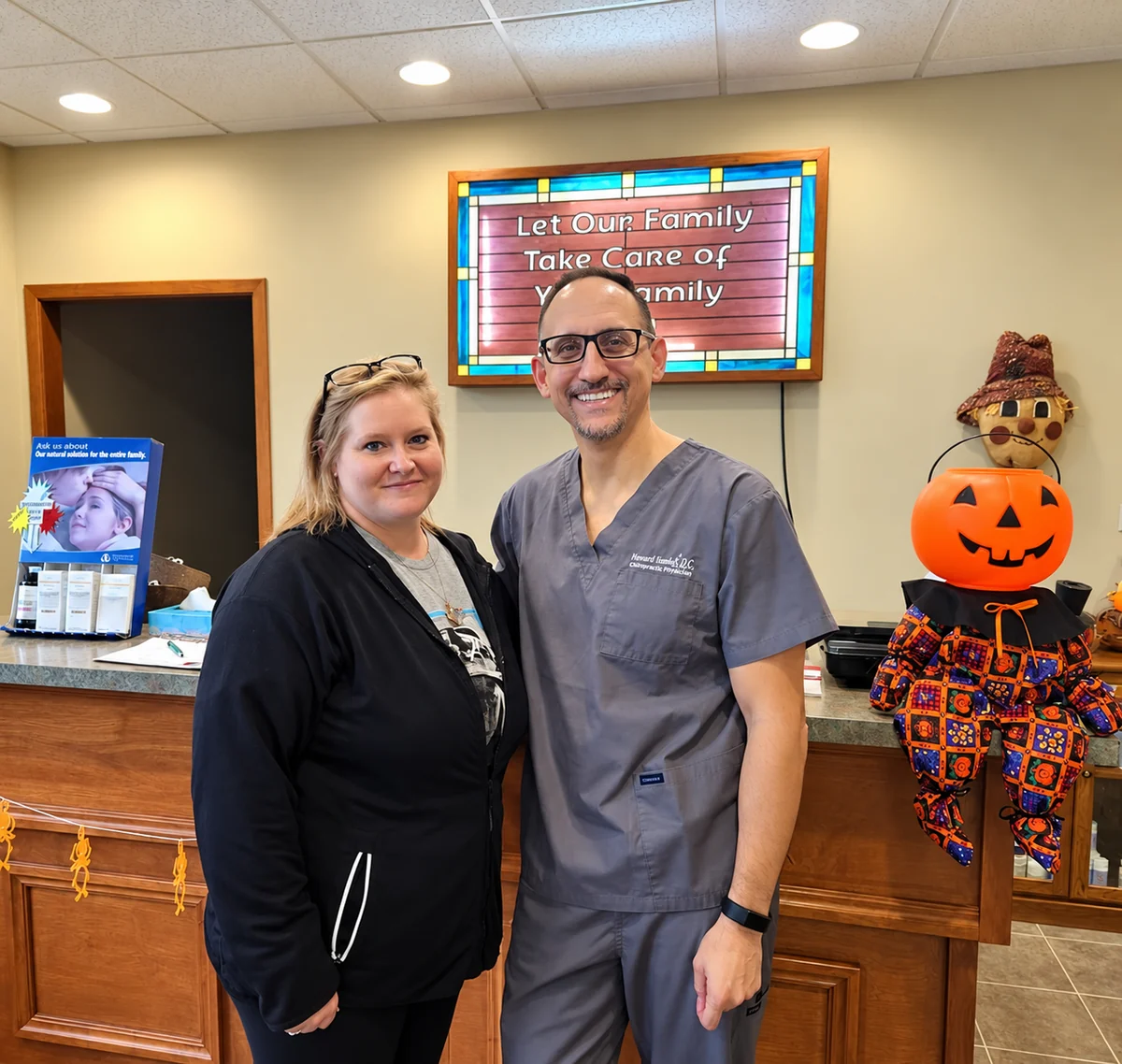 Two people smiling together at the Freeport Family Chiropractic reception desk
